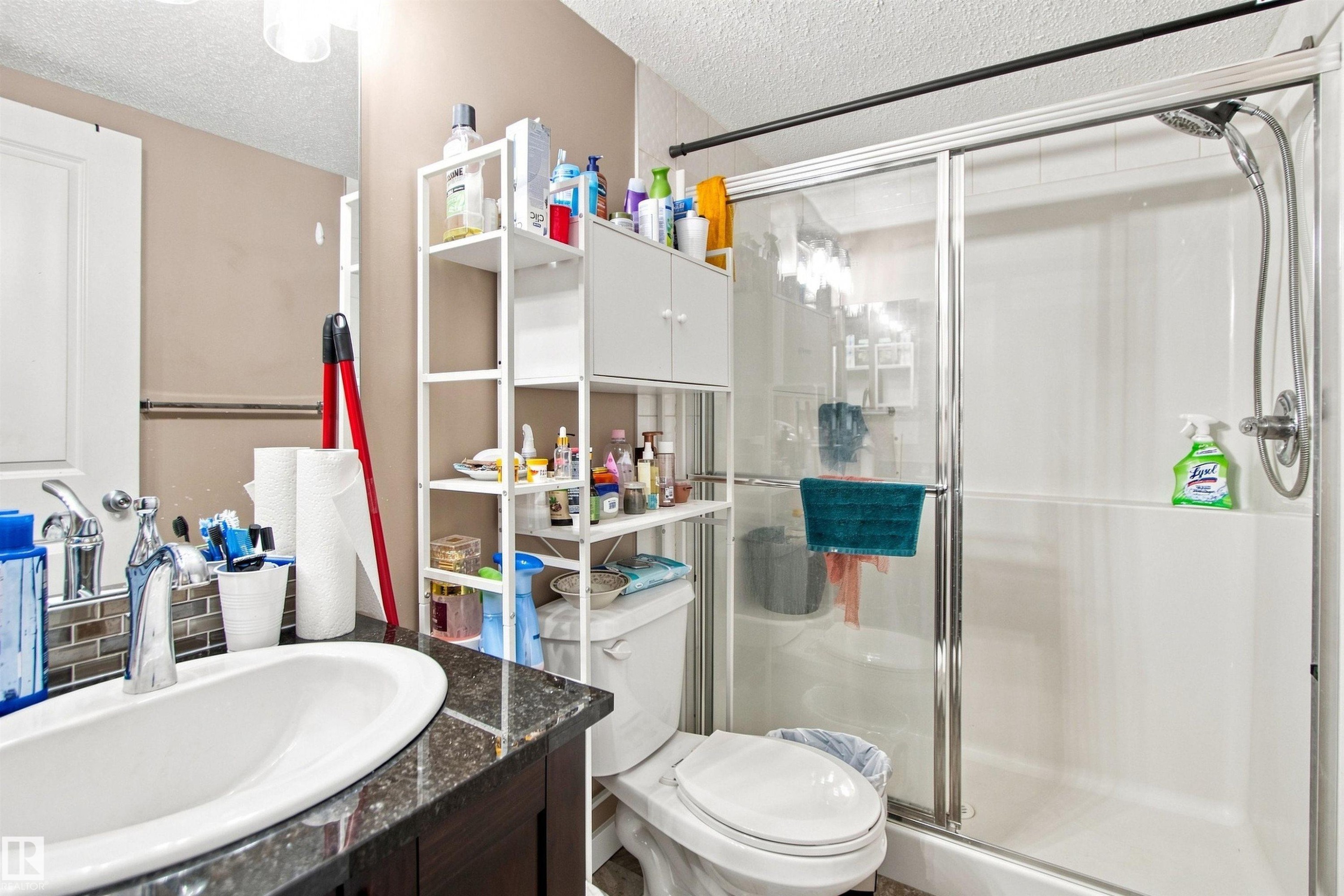 Vanity with an oval undermount sink, mosaic tile backsplash, and dark granite-style countertop - #413 18126 77 St Nw, Edmonton, AB
