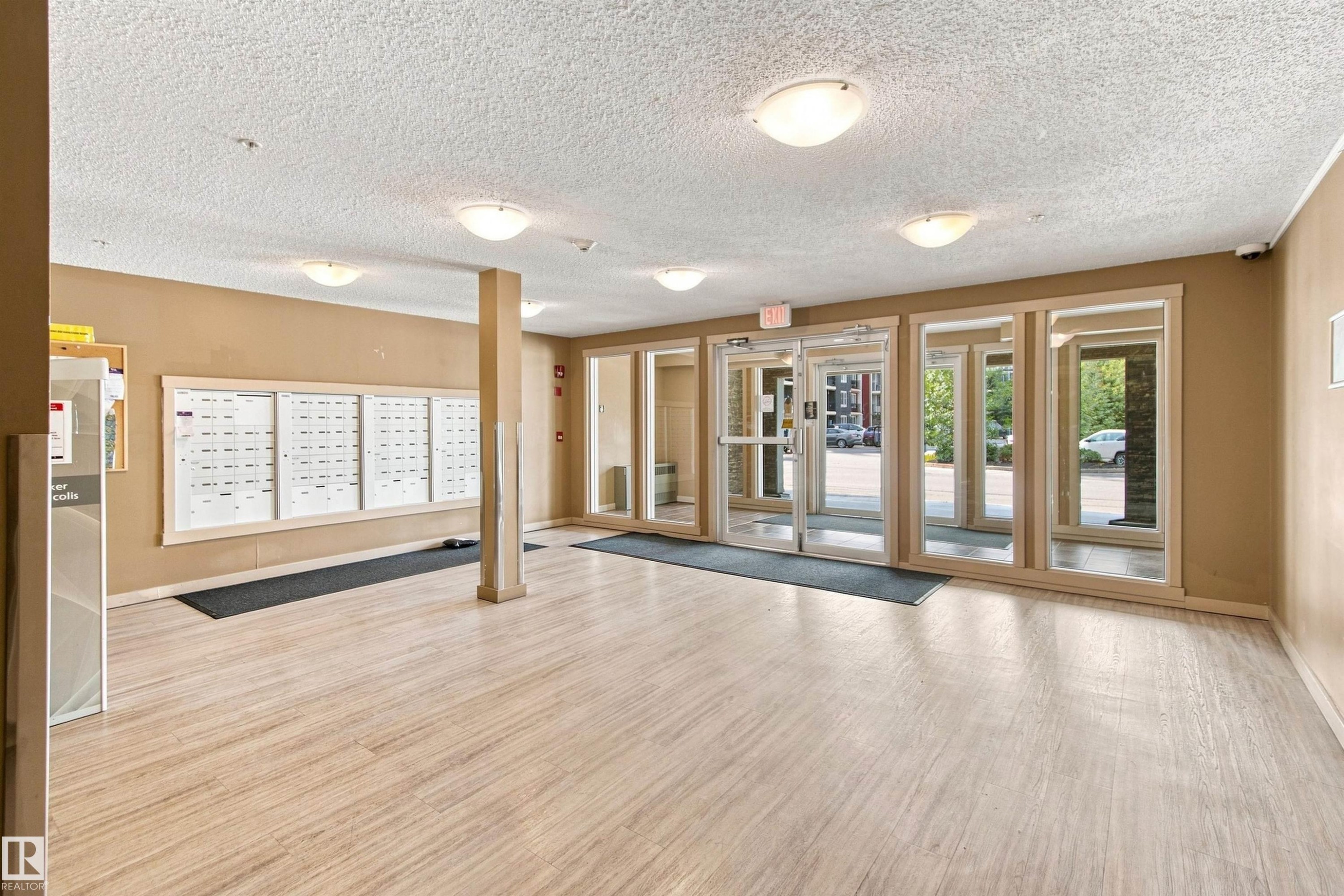 Entrance foyer with wood-finish flooring, flush mount lighting, and large window panels - #413 18126 77 St Nw, Edmonton, AB