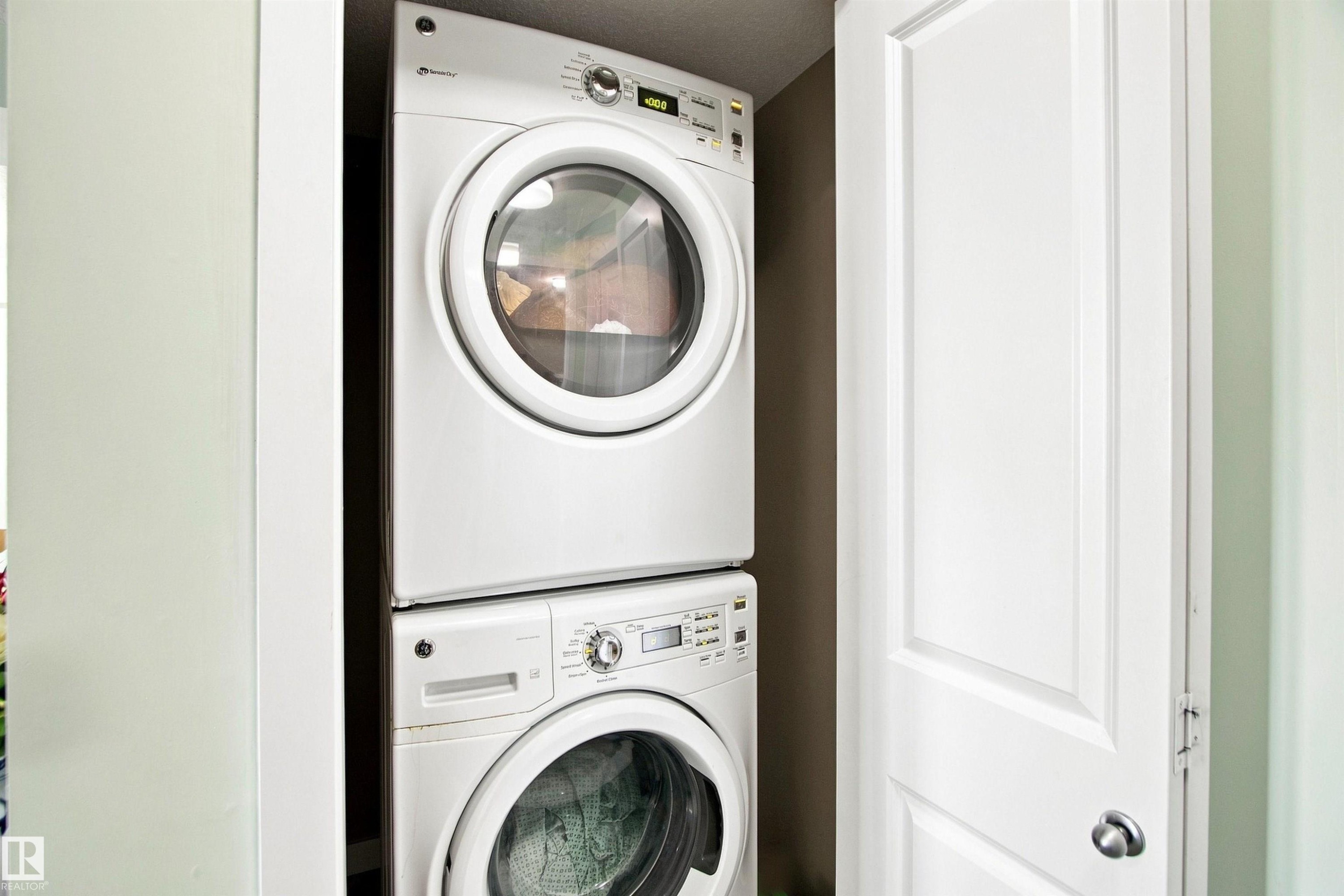 Stacked washer and dryer unit, white paneled door, and light wall finishes - #413 18126 77 St Nw, Edmonton, AB