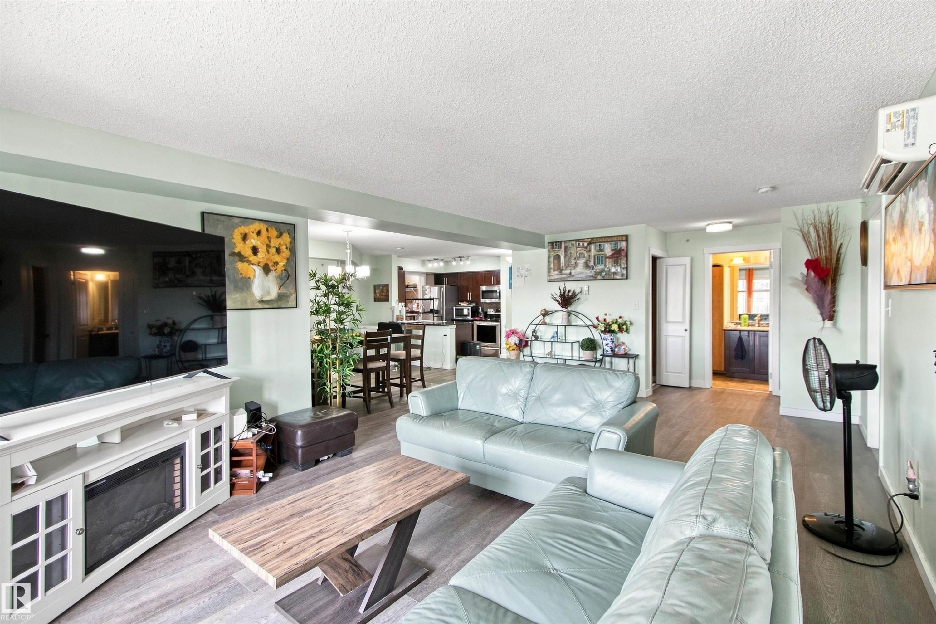 Wood-finish flooring throughout, a built-in electric fireplace, and an open-concept layout - #413 18126 77 St Nw, Edmonton, AB