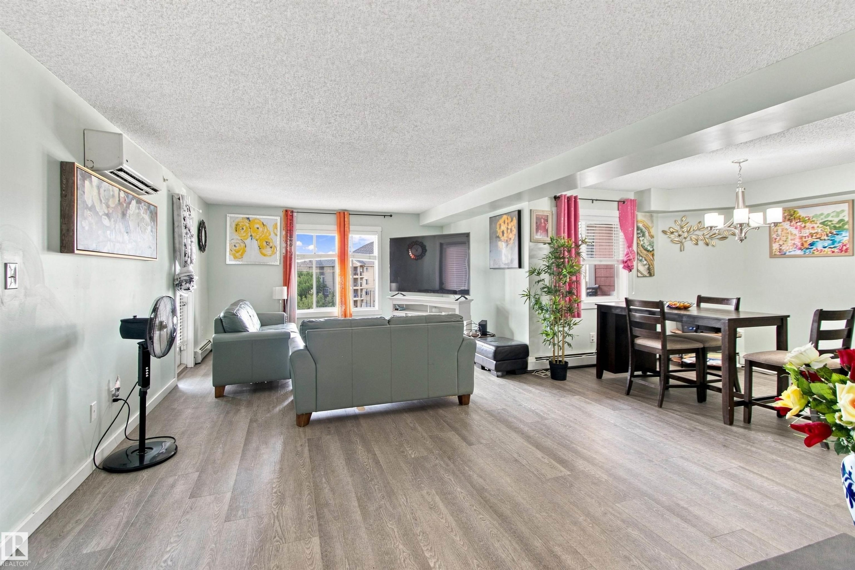 Open-concept living space featuring wood-finish flooring, recessed lighting, and ample natural light from multiple windows - #413 18126 77 St Nw, Edmonton, AB