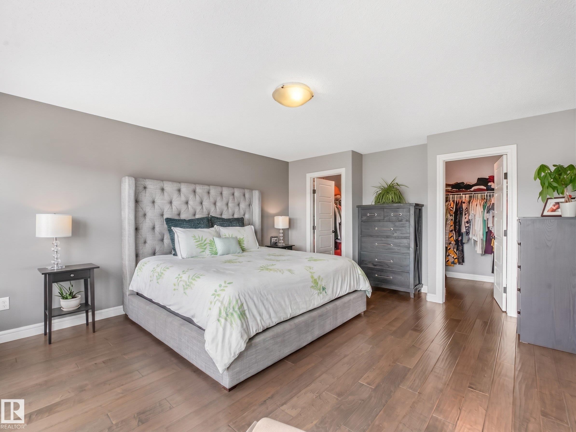A spacious primary suite featuring his-and-hers walk-in closets and private access to a beautiful balcony overlooking the expansive backyard. - 3711 Westcliff Way Sw, Edmonton, AB