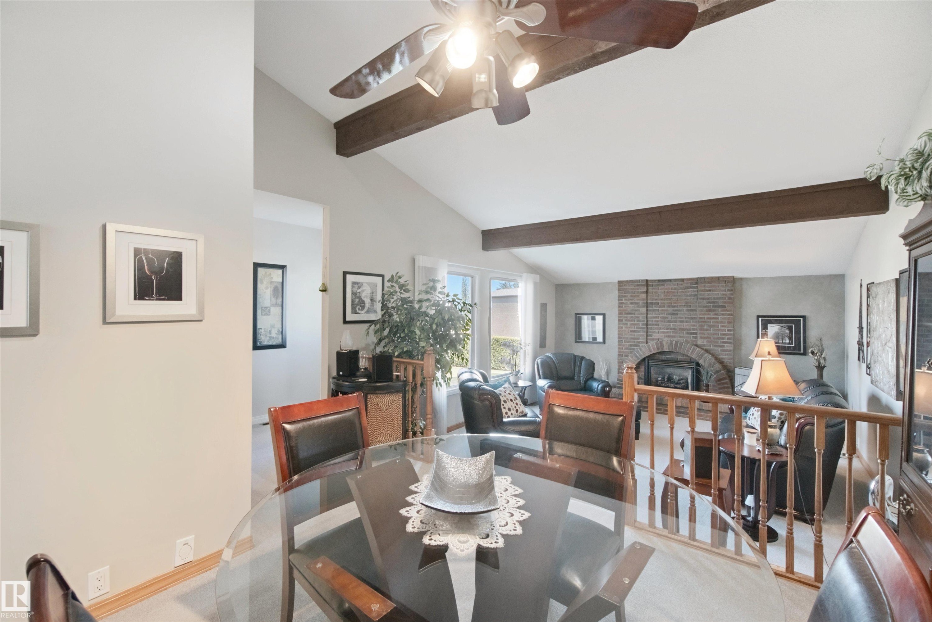 Vaulted ceilings with exposed wood beams, a brick fireplace with an arched opening, a ceiling fan, and solar tube skylight - 11439 144 Avenue Nw, Edmonton, AB