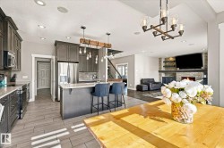 Open-concept living area with a stone-clad fireplace, integrated shelving, and recessed lighting - 