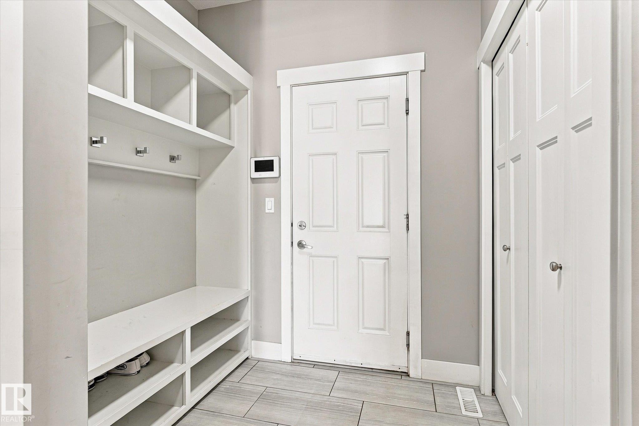Built-in storage bench with open shelving, wall-mounted coat hooks, and multi-panel doors - 2011 Genesis Lane, Stony Plain, AB