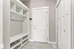 Built-in storage bench with open shelving, wall-mounted coat hooks, and multi-panel doors - 