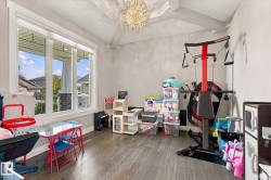 Vaulted ceiling with an ornate light fixture, large multi-pane window, and wood-finish flooring - 