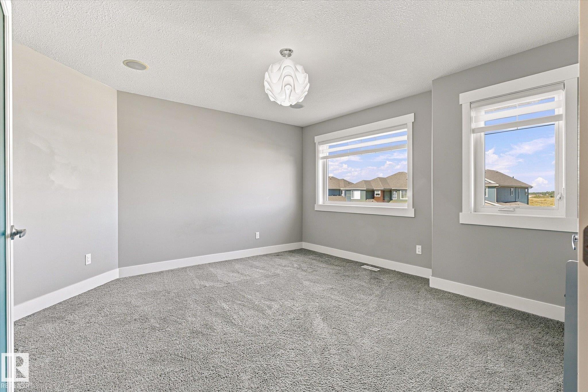 Neutral wall color, wall-to-wall carpeting, recessed ceiling lighting, overhead chandelier, and multiple windows - 2011 Genesis Lane, Stony Plain, AB