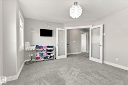 Plush carpet flooring, neutral wall tones, decorative ceiling light fixture, and French doors with frosted panels - 