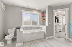 Recessed lighting, a built-in bathtub with a tiled surround, and wood-finish flooring - 