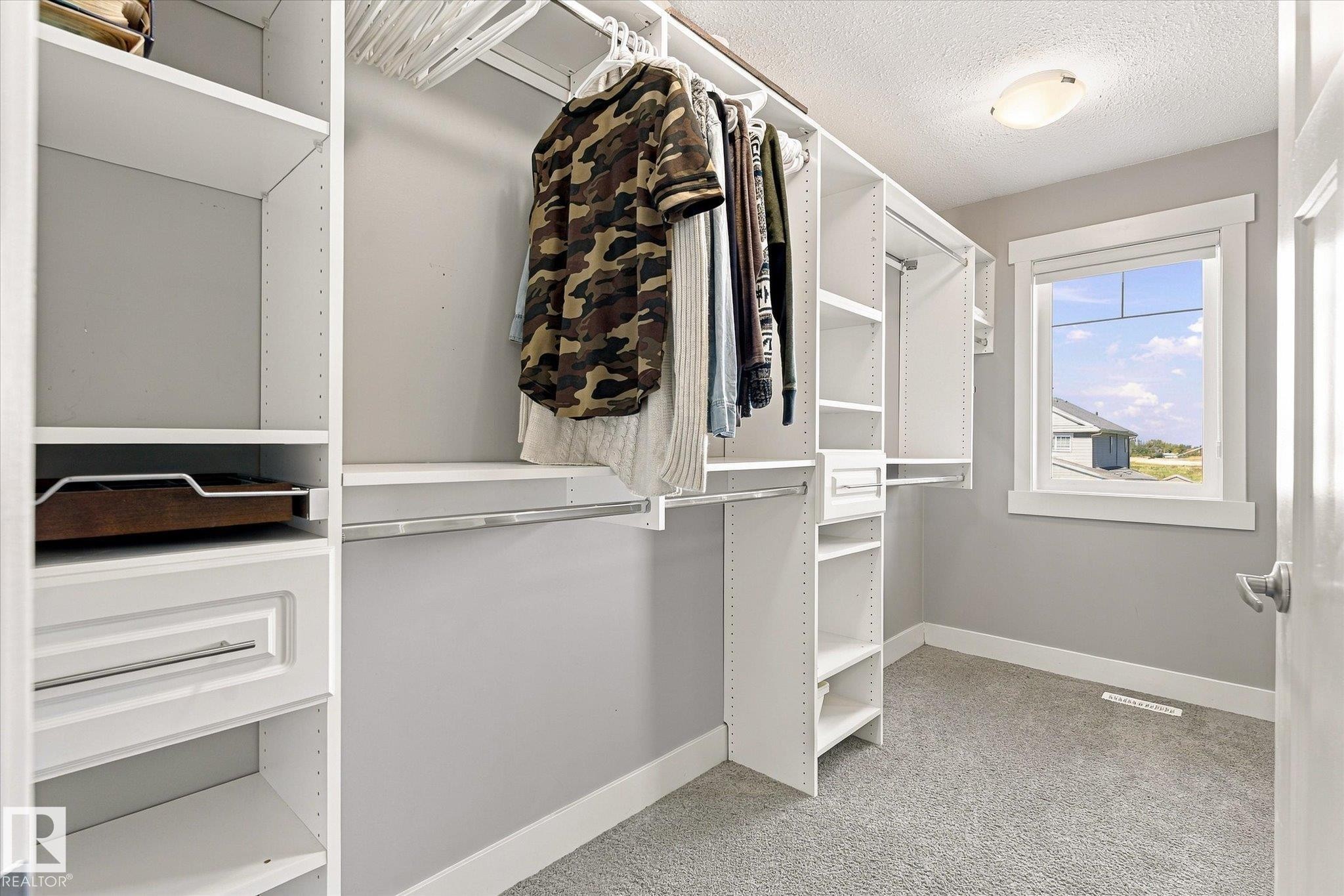 Custom closet system with multiple shelving units, hanging rods, and built-in drawers - 2011 Genesis Lane, Stony Plain, AB