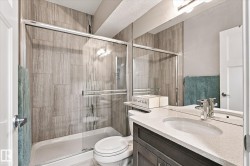 Bathroom featuring a shower with glass enclosure, wood-finish wall tile, a single vanity with stone-finish countertop, and integrated sink - 