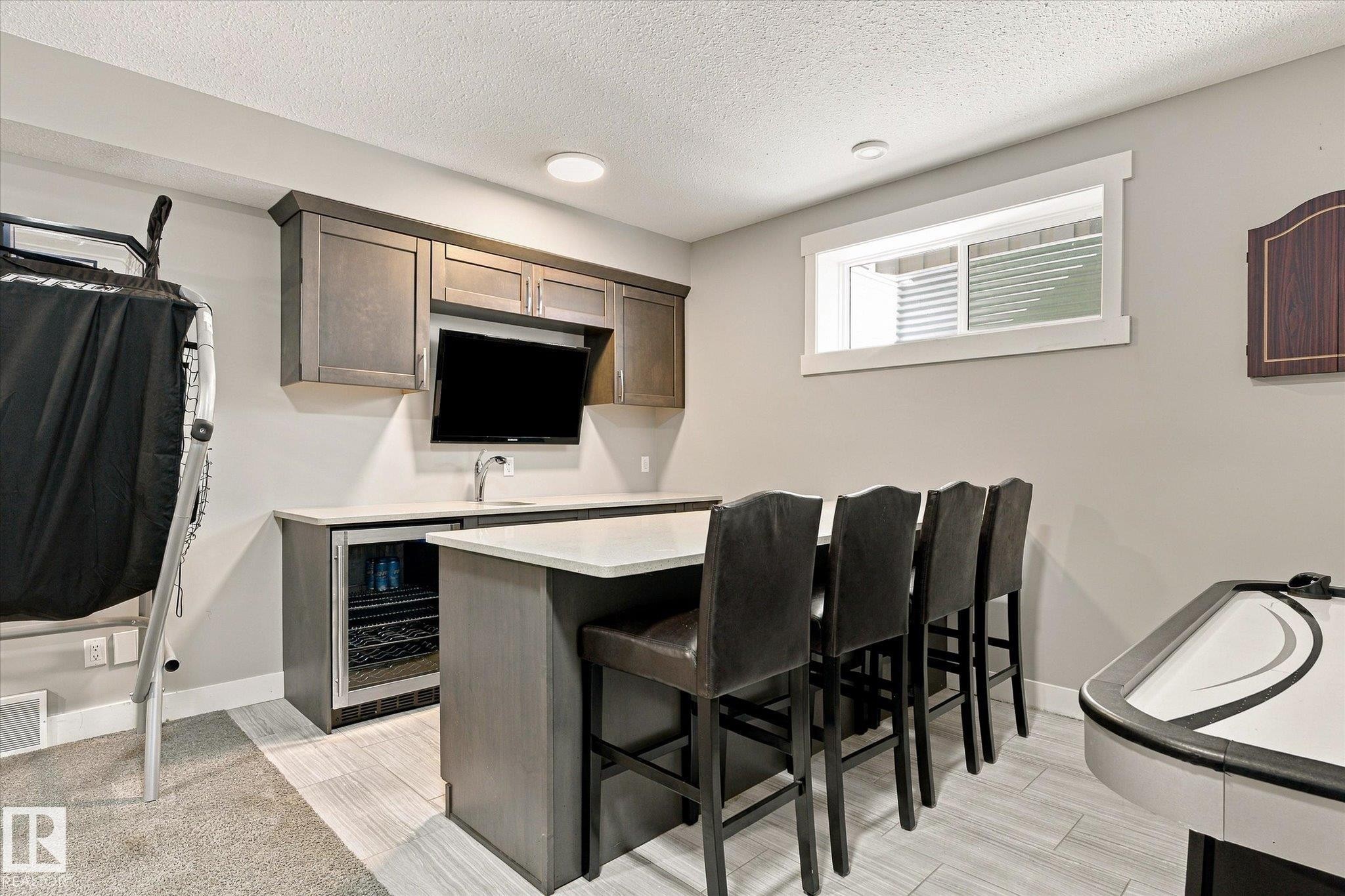 Built-in wet bar with wood-finish cabinetry, integrated beverage refrigerator, undermount sink, and recessed lighting - 2011 Genesis Lane, Stony Plain, AB