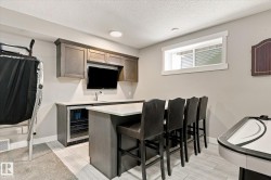 Built-in wet bar with wood-finish cabinetry, integrated beverage refrigerator, undermount sink, and recessed lighting - 