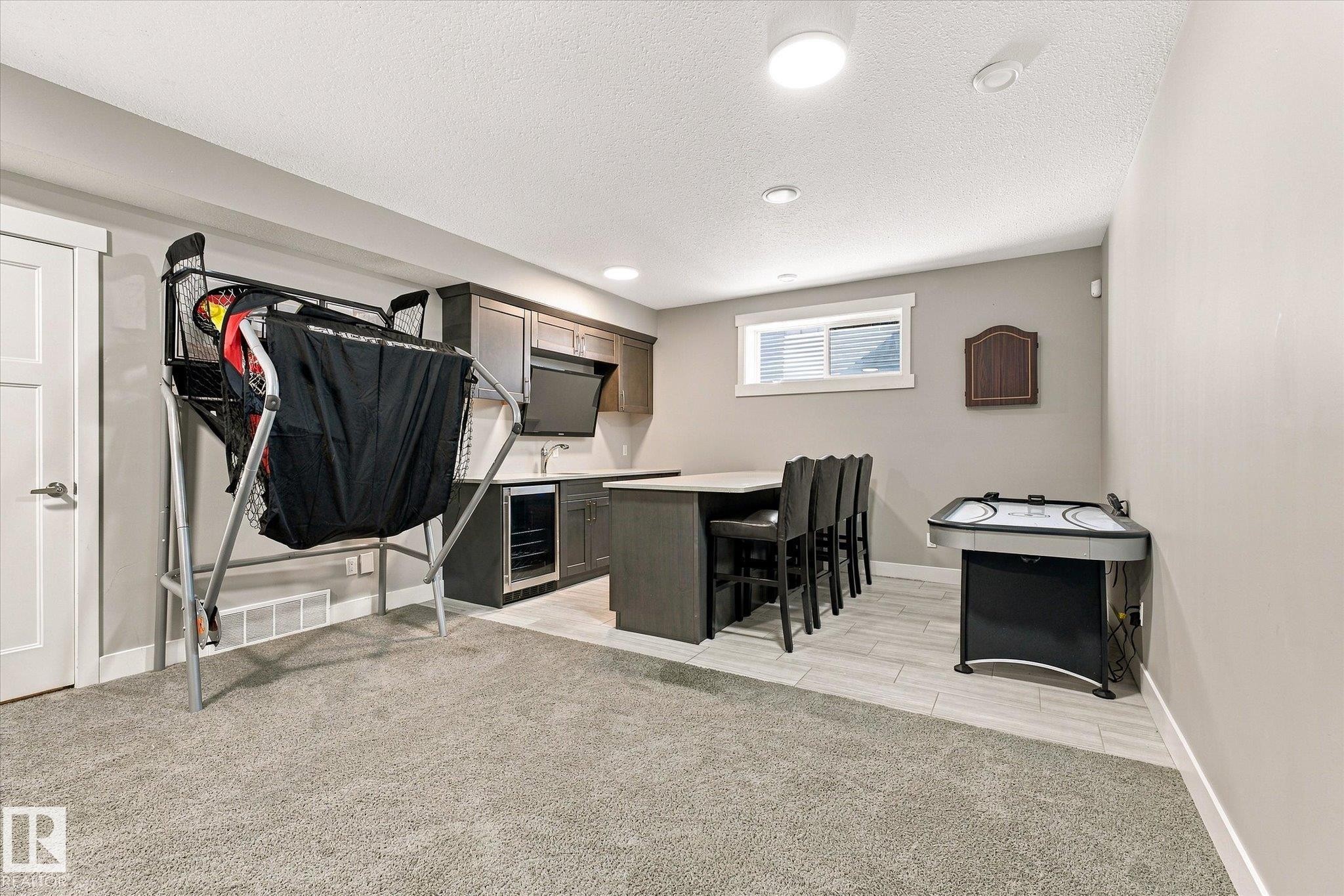 Built-in wet bar with dark cabinetry, integrated beverage refrigerator, and countertop seating - 2011 Genesis Lane, Stony Plain, AB