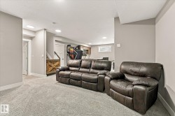 Recessed lighting illuminates the carpeted flooring and light grey walls - 