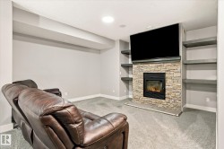 Recessed lighting, built-in shelving, stone-faced fireplace with hearth, and carpeted flooring - 
