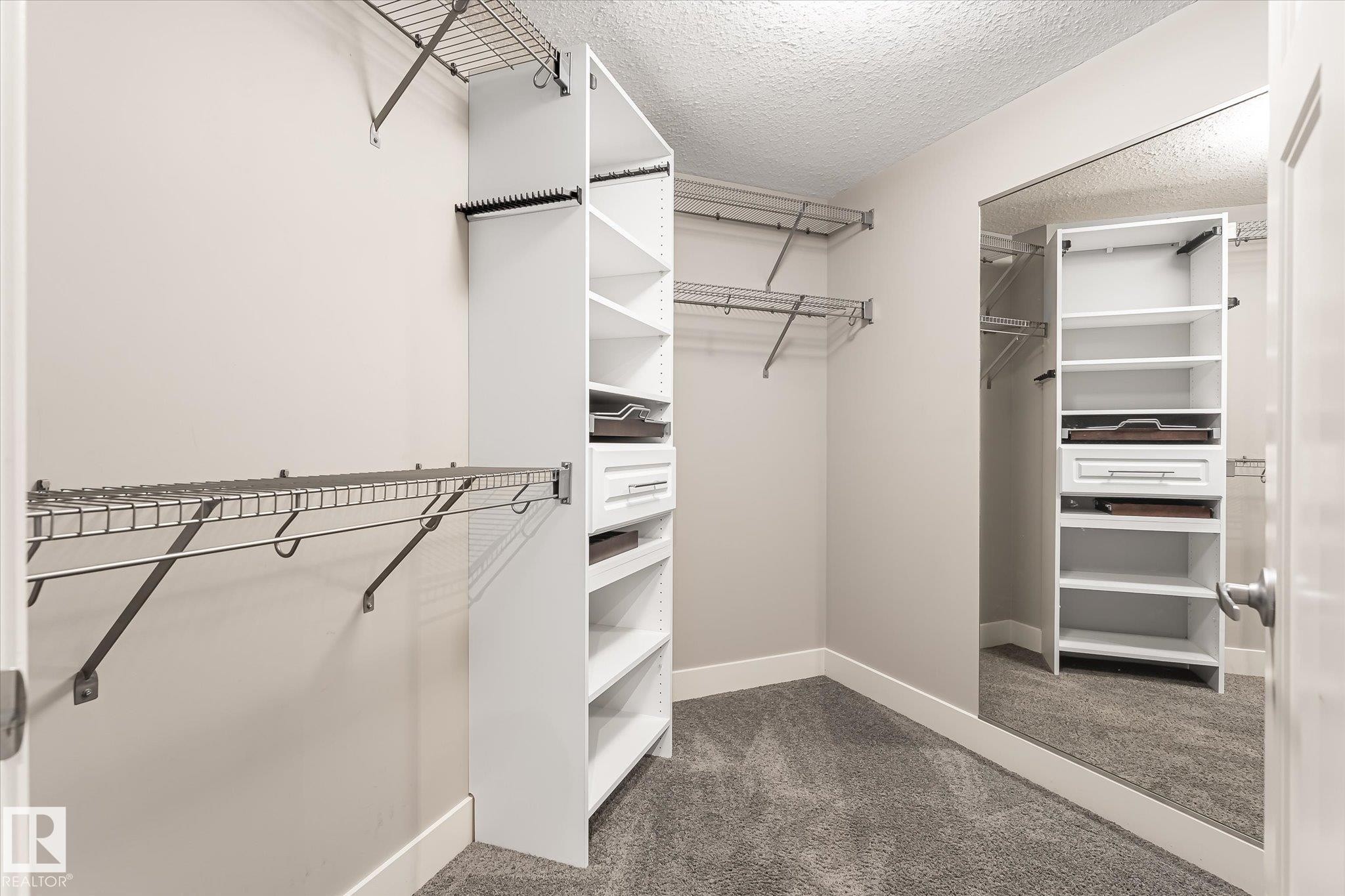 Walk-in closet featuring wire shelving, built-in white cabinetry, drawer storage, and full-length mirror - 2011 Genesis Lane, Stony Plain, AB