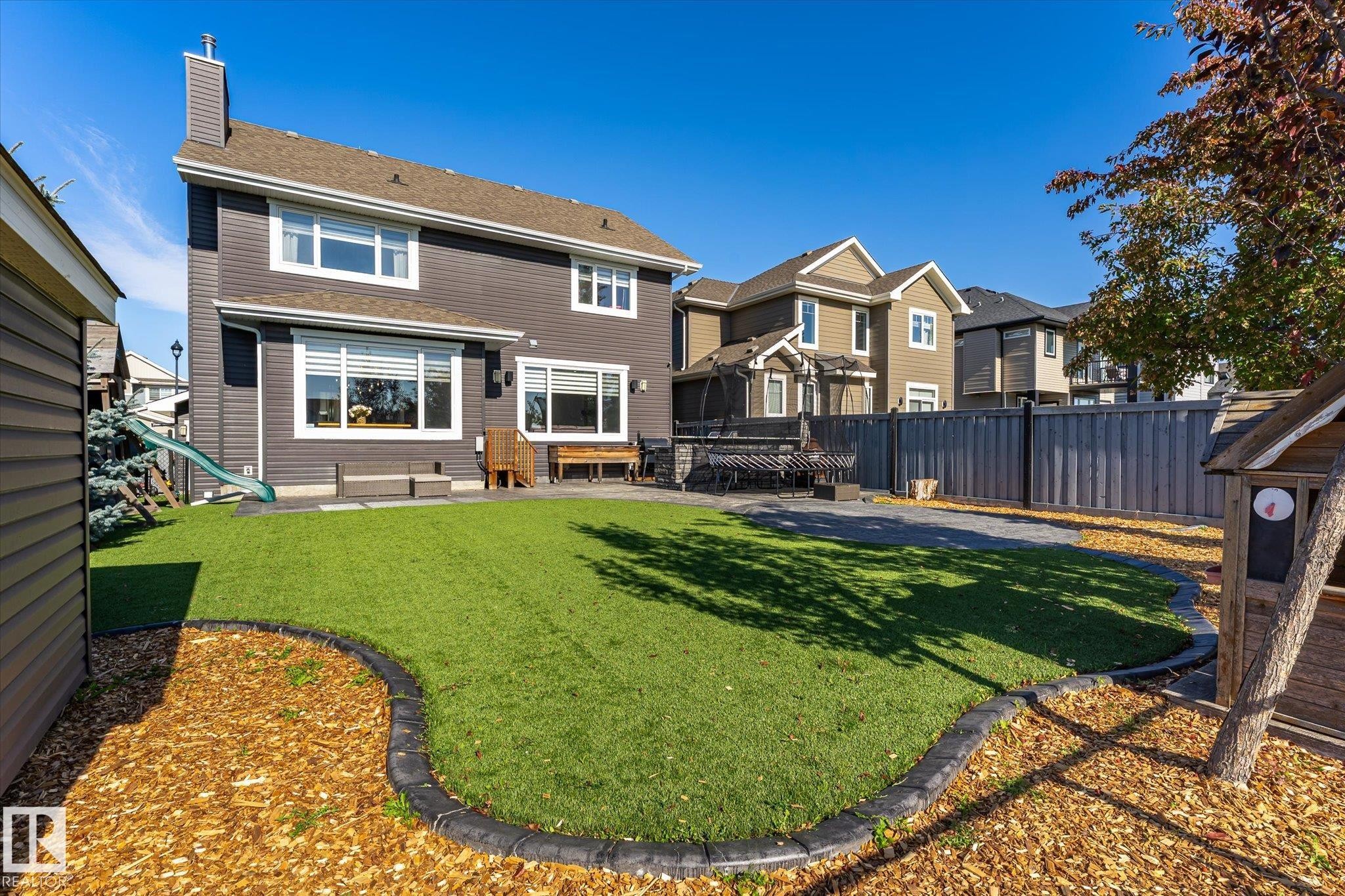 Manicured green lawn with decorative border, spacious patio, and privacy fencing - 2011 Genesis Lane, Stony Plain, AB