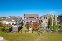 Expansive fenced backyard featuring a manicured lawn, mature landscaping, and a utility shed - 