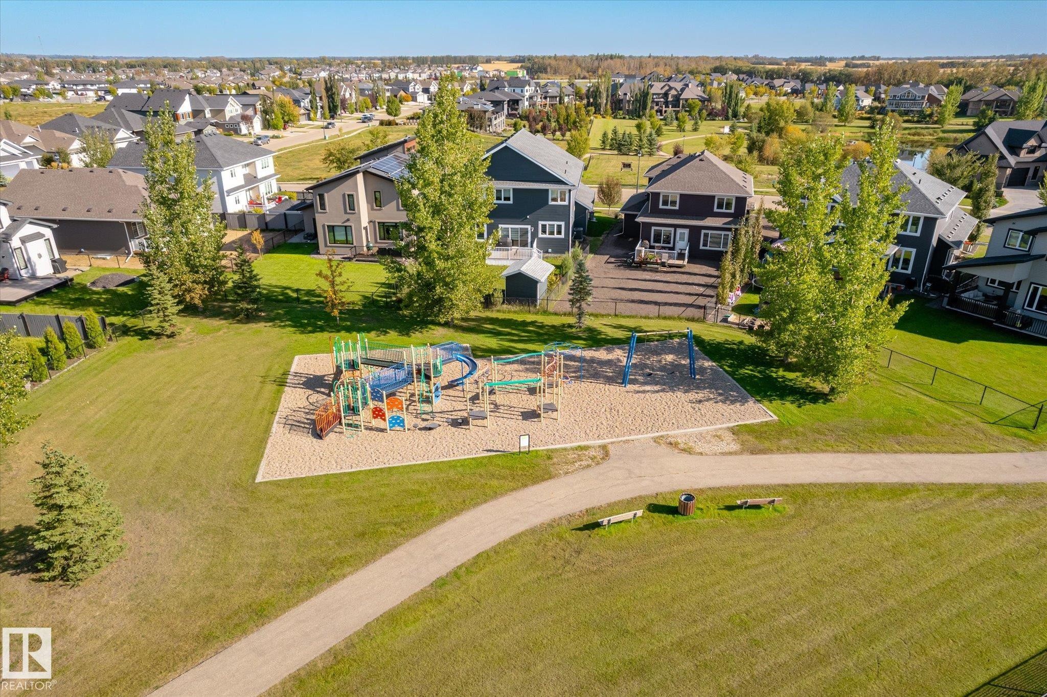 Community playground area with a multi-level play structure and swing set - 2011 Genesis Lane, Stony Plain, AB