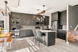Modern kitchen featuring dark wood-finish cabinetry, stainless steel appliances, a center island with seating, and wood-finish tile flooring - 
