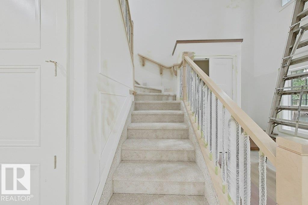 Carpeted staircase with light wood handrails and wrought iron balusters - 9216 91 Street Nw, Edmonton, AB - Indoor Photo Showing Other Room