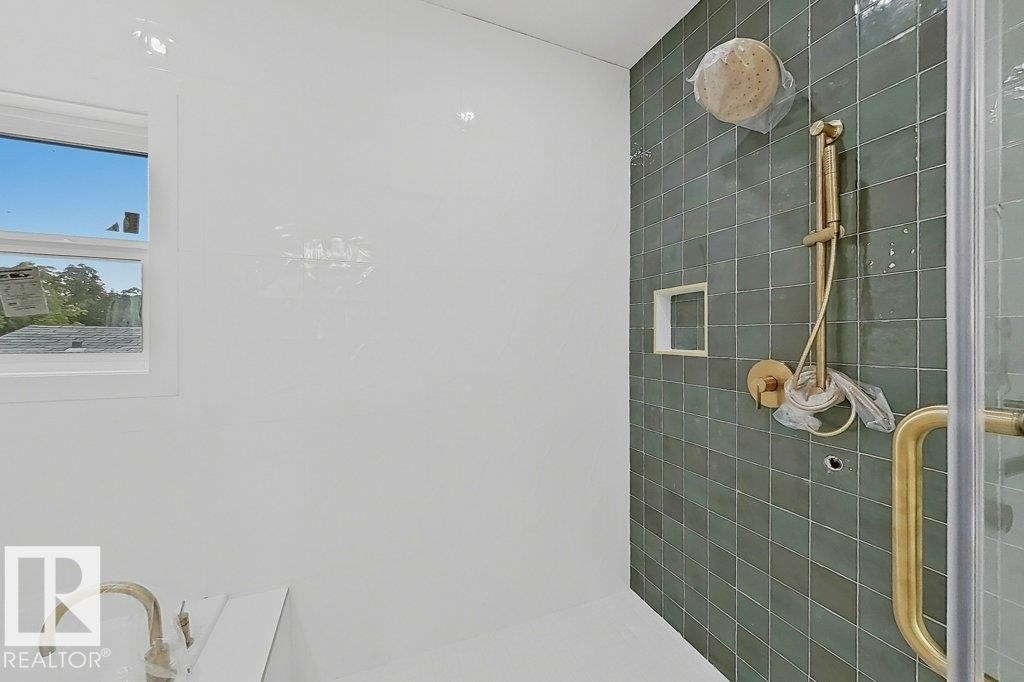 Shower with green tile surround and gold-toned fixtures, including a rain shower head and handheld sprayer - 9216 91 Street Nw, Edmonton, AB - Indoor