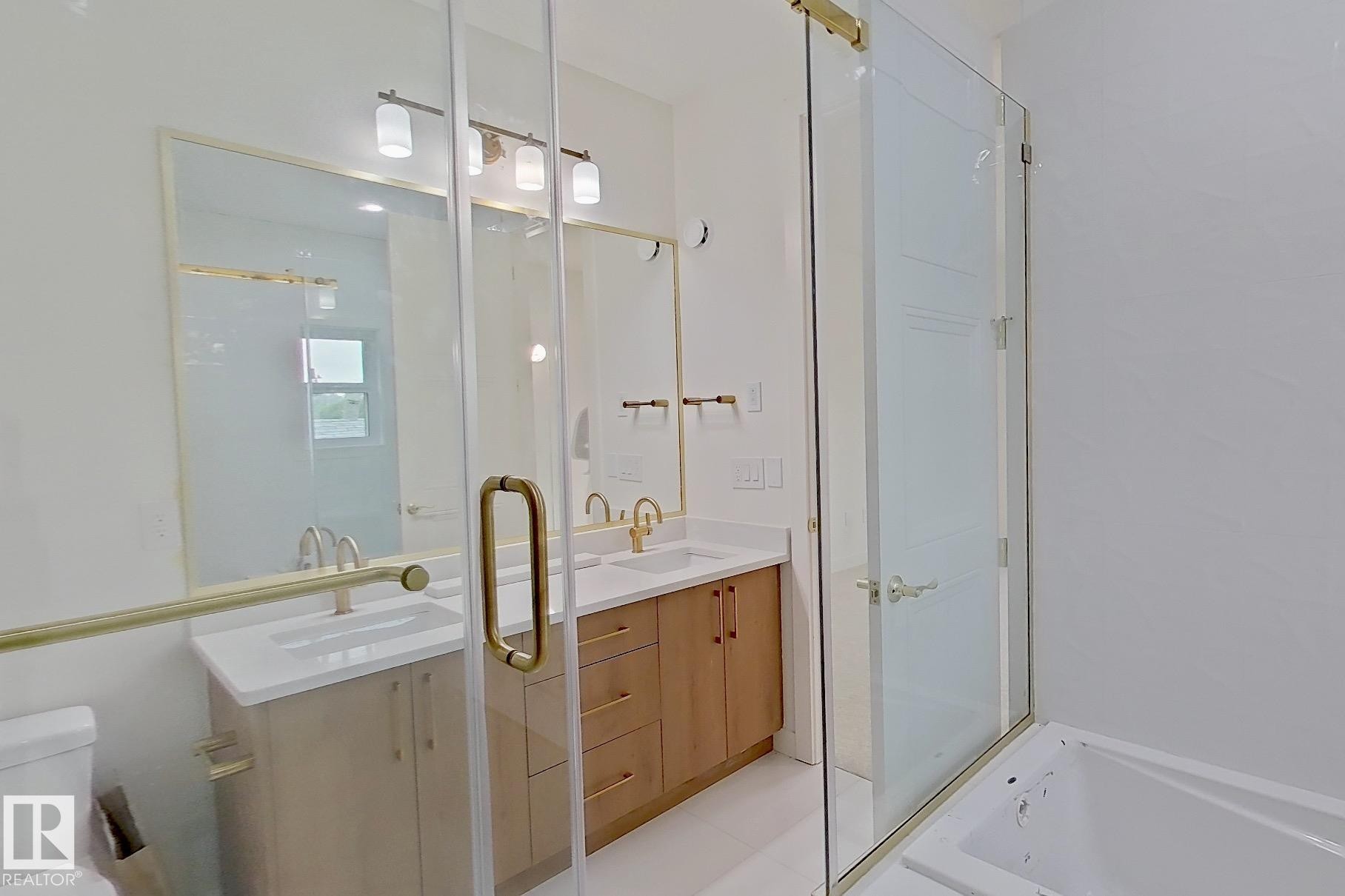 Modern bathroom featuring a dual vanity with light-tone wood cabinetry, white countertops, and gold-finish hardware - 9216 91 Street Nw, Edmonton, AB - Indoor Photo Showing Other Room