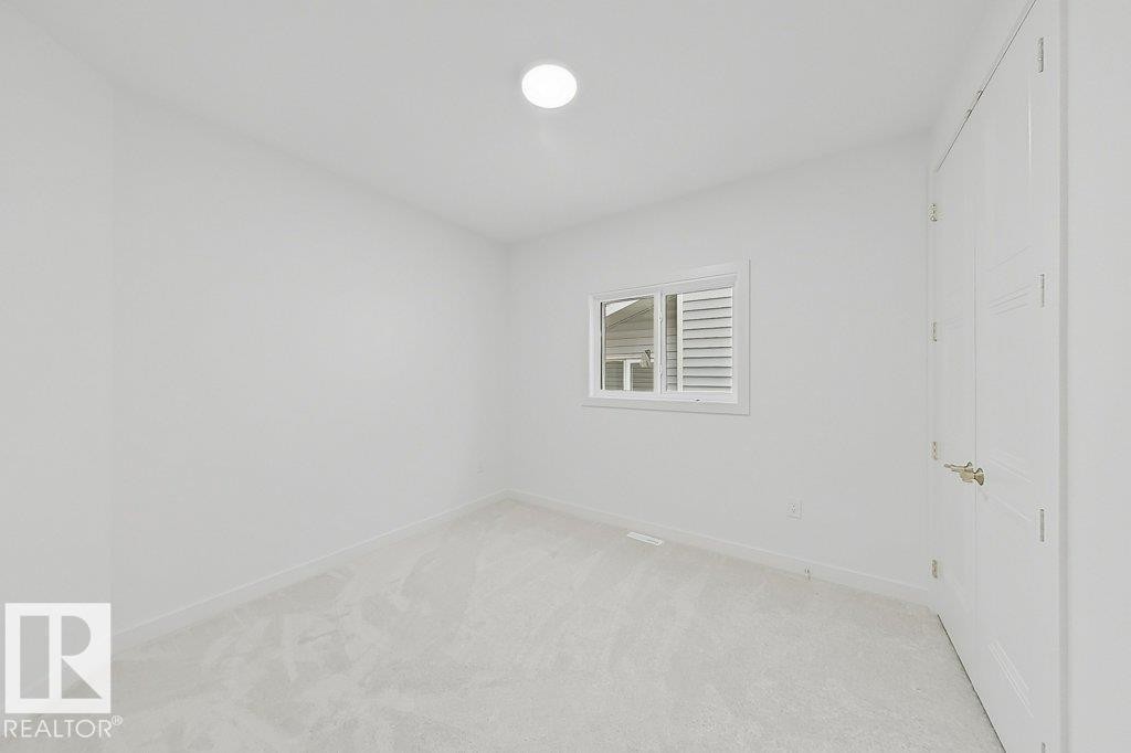 Neutral white wall paint, light-colored carpeting, white trim, a single window, and a white interior door with brushed nickel hardware - 9216 91 Street Nw, Edmonton, AB - Indoor Photo Showing Bathroom