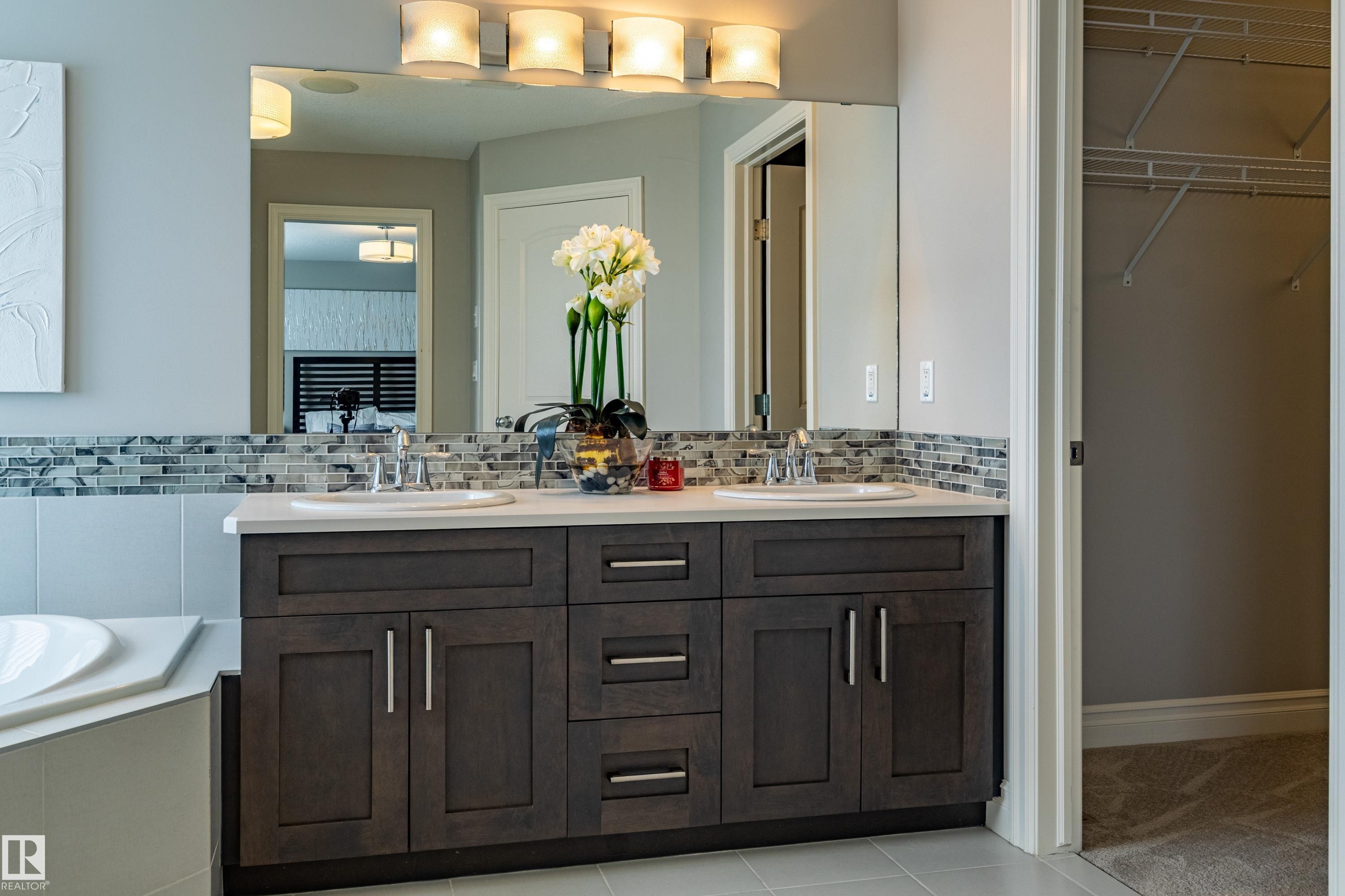 Dual vanity with white undermount sinks, stone countertop, and mosaic tile backsplash - 233 Hawks Ridge Boulevard Nw, Edmonton, AB