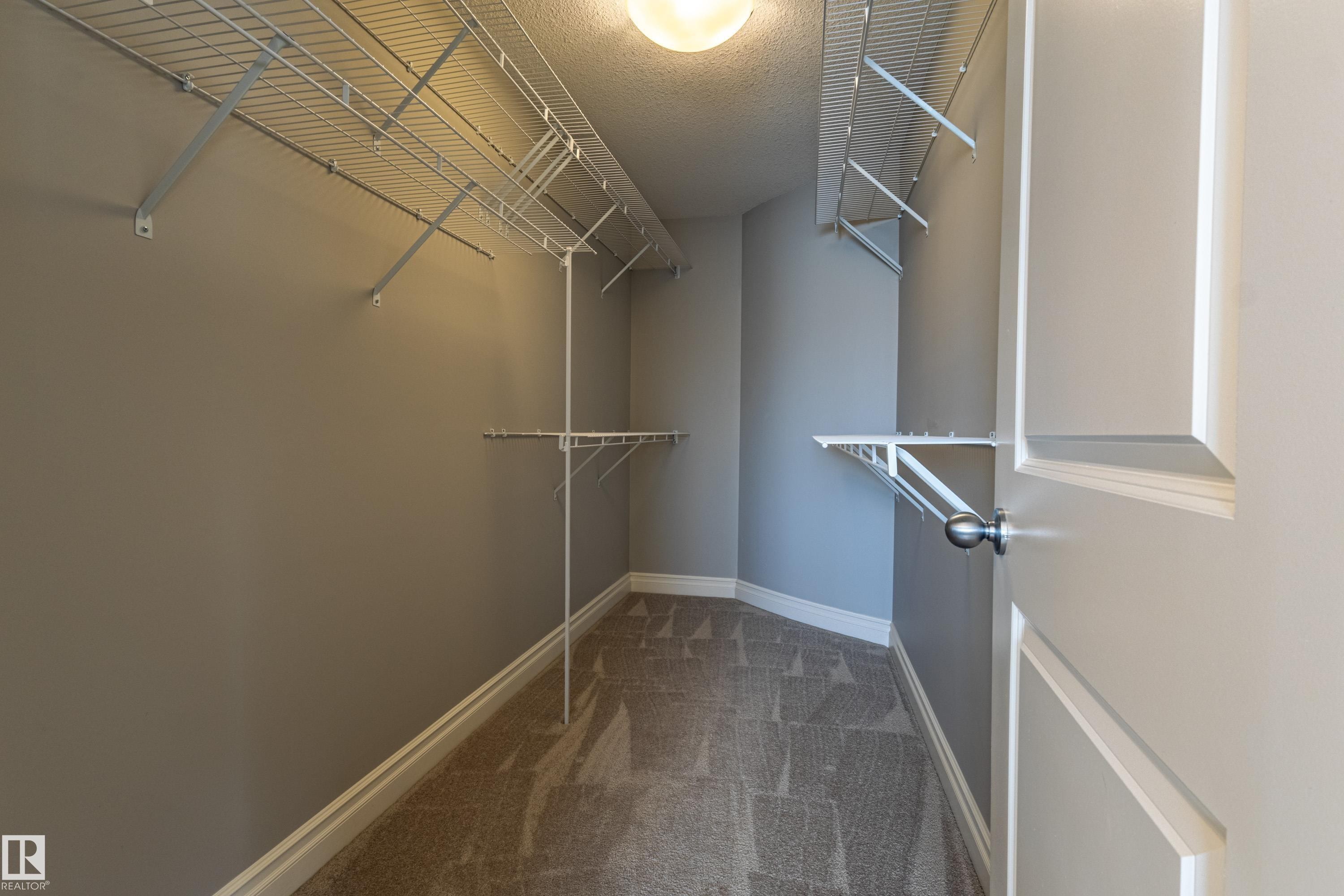 Walk-in closet featuring carpet flooring, neutral wall tones, and extensive wire shelving - 233 Hawks Ridge Boulevard Nw, Edmonton, AB