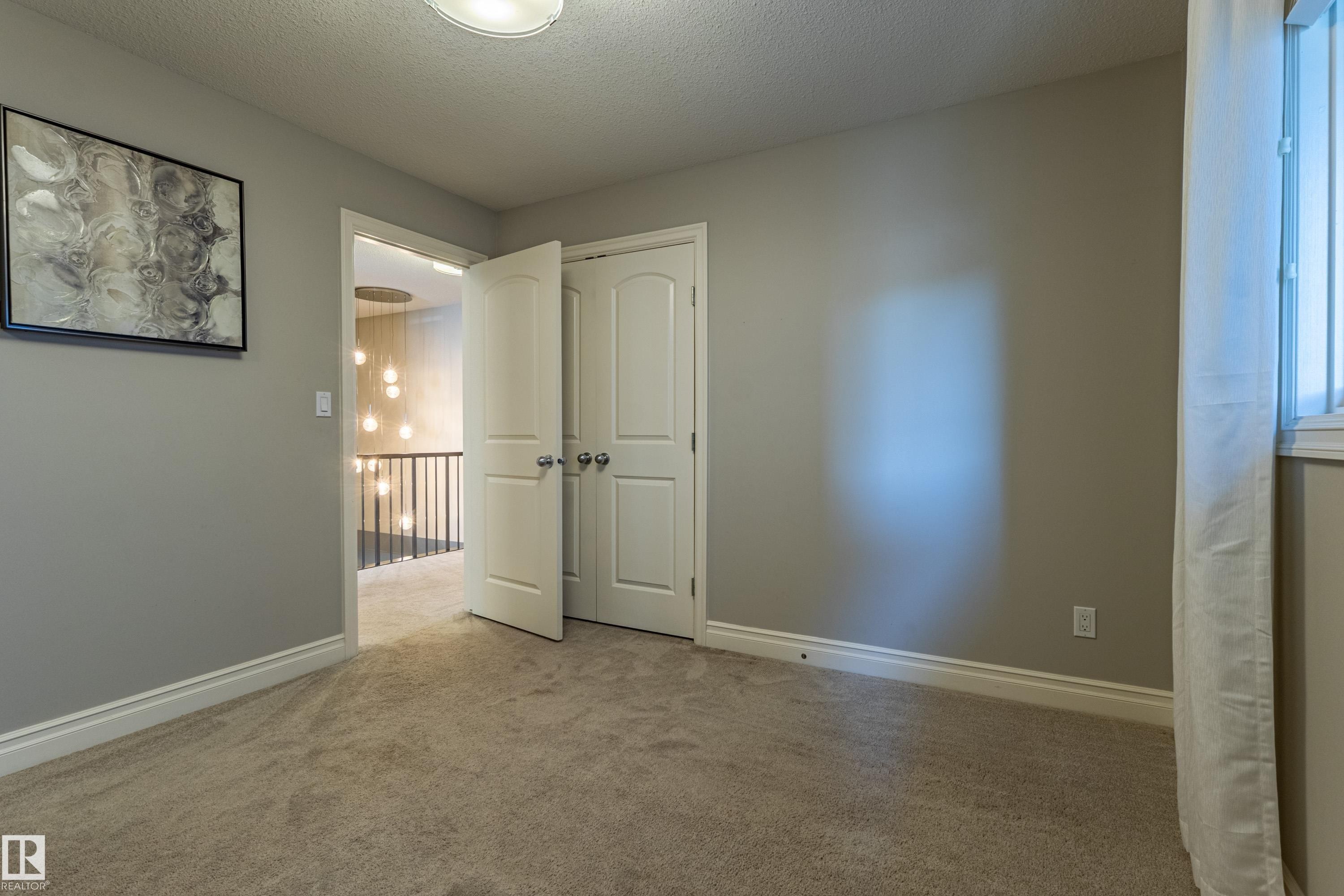 Neutral wall paint with white trim, carpeting, and a window with white window casing - 233 Hawks Ridge Boulevard Nw, Edmonton, AB
