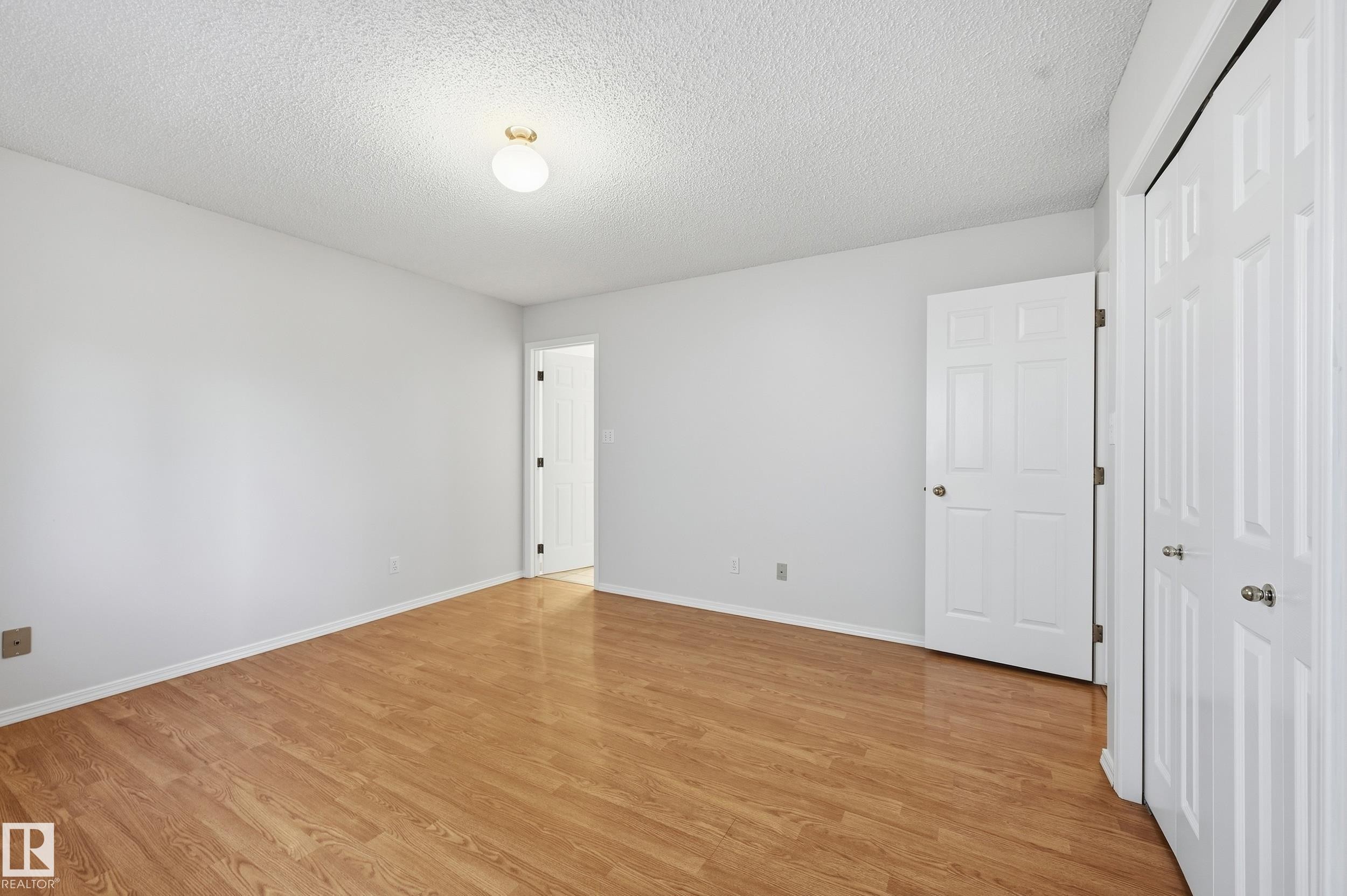 Light wood-finish flooring, white walls, and a popcorn ceiling - 11102 11A Avenue Nw, Edmonton, AB