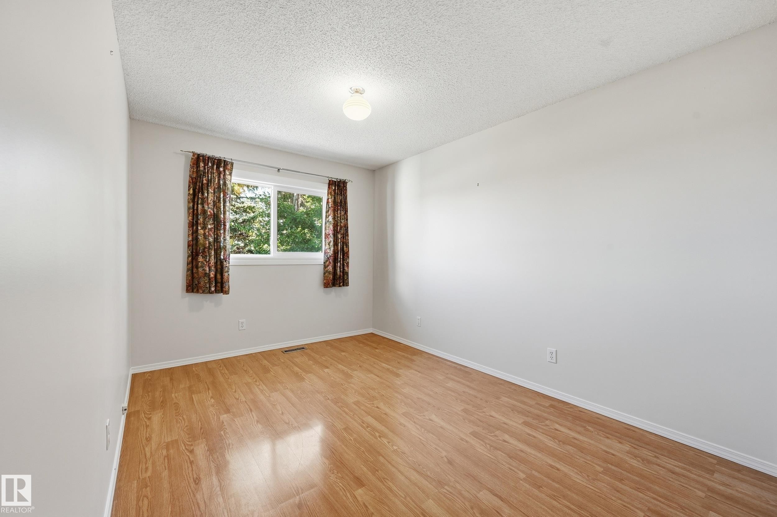 Light wood-finish flooring, white walls, and a window with a natural outdoor backdrop - 11102 11A Avenue Nw, Edmonton, AB