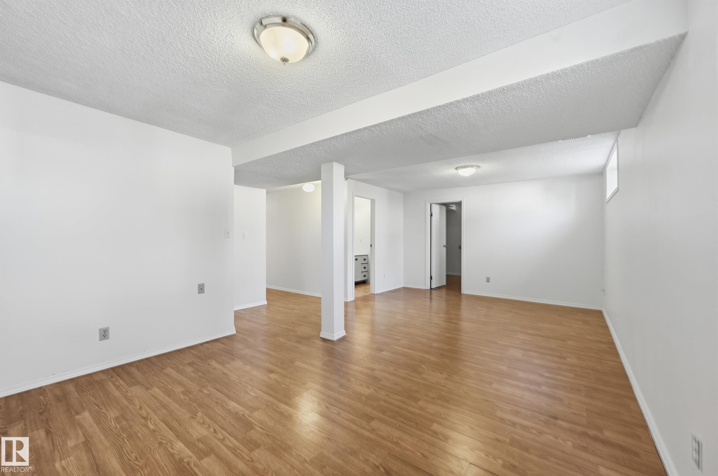 Expansive room with wood-finish flooring, white walls, and recessed lighting - 11102 11A Avenue Nw, Edmonton, AB