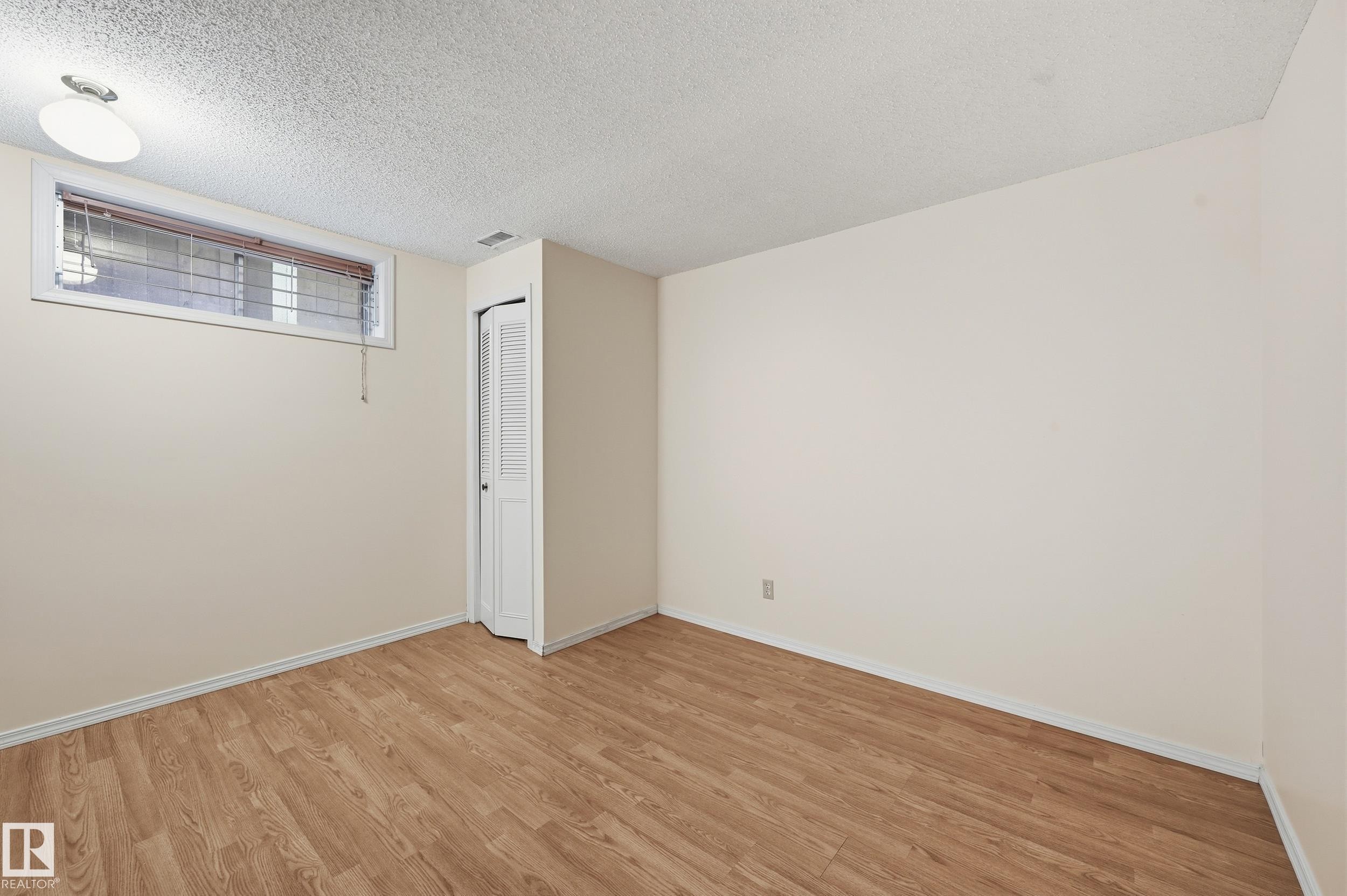 Wood-finish flooring, neutral wall tones, and bi-fold closet doors - 11102 11A Avenue Nw, Edmonton, AB