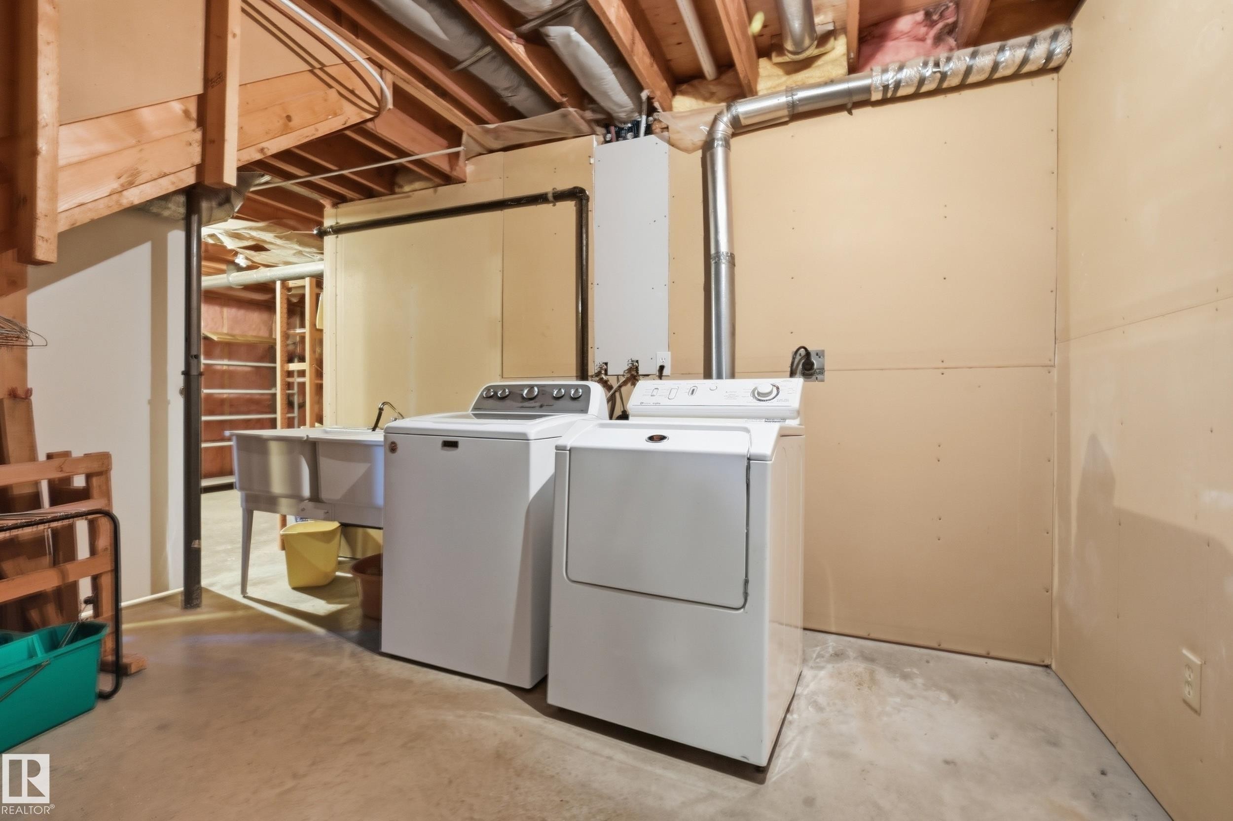 Laundry area featuring a utility sink, concrete flooring, and exposed ceiling joists - 11102 11A Avenue Nw, Edmonton, AB