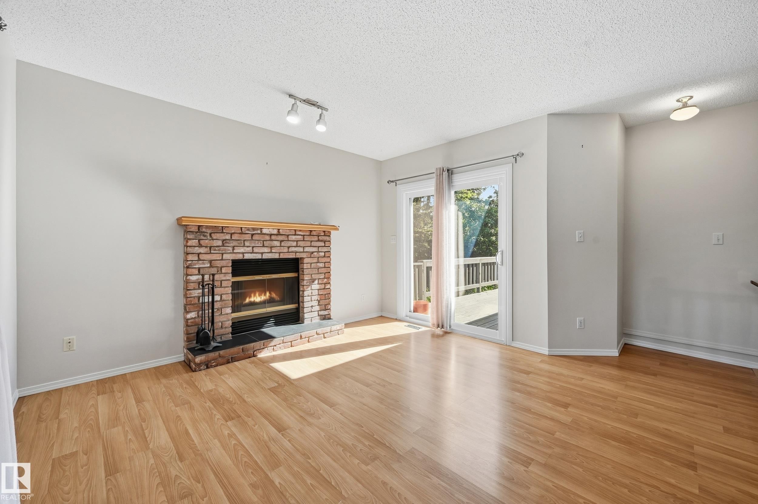 Wood-finish flooring with a brick fireplace, complete with a natural wood mantel - 11102 11A Avenue Nw, Edmonton, AB