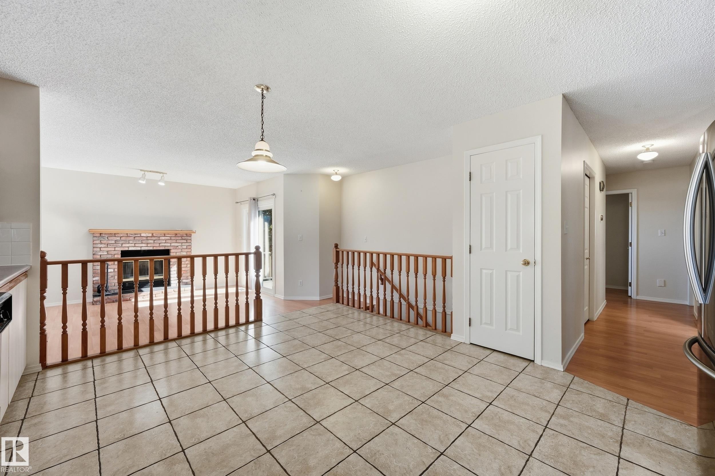 Tiled flooring, wood-finish railings, brick fireplace, recessed lighting, and wood-finish flooring in the hallway - 11102 11A Avenue Nw, Edmonton, AB
