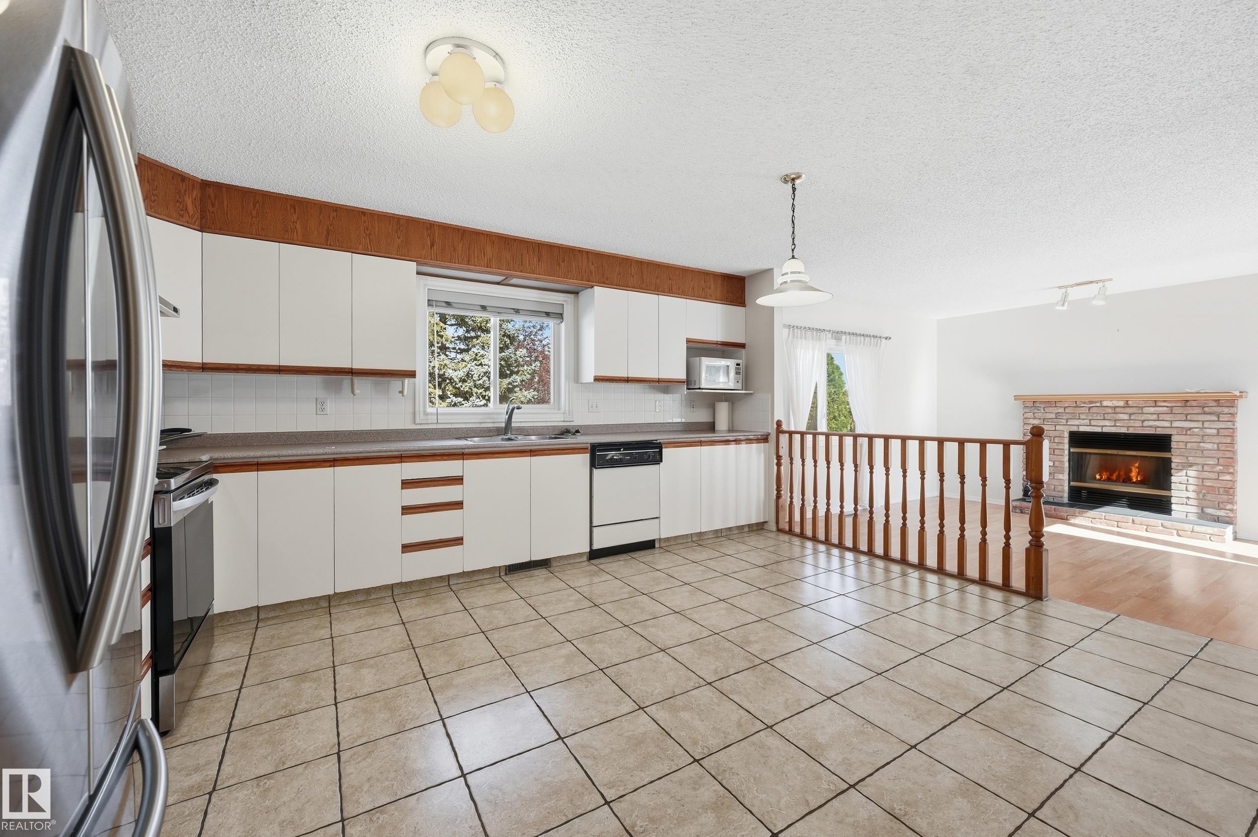 Kitchen featuring white cabinetry, a stainless steel refrigerator, and tiled flooring - 11102 11A Avenue Nw, Edmonton, AB