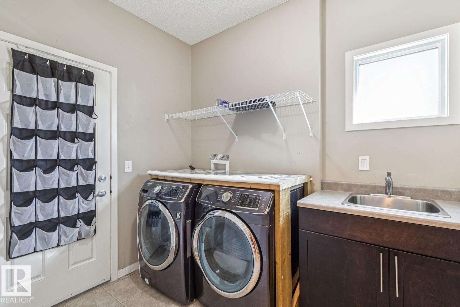 Laundry area with a built-in sink, dark wood-finish cabinetry, and a window - 12007 173 Avenue Nw, Edmonton, AB