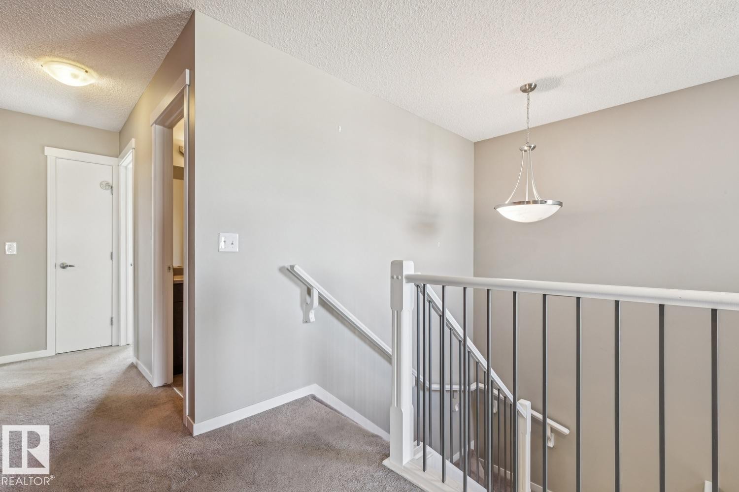 Staircase featuring a white handrail and black metal spindles - 12007 173 Avenue Nw, Edmonton, AB