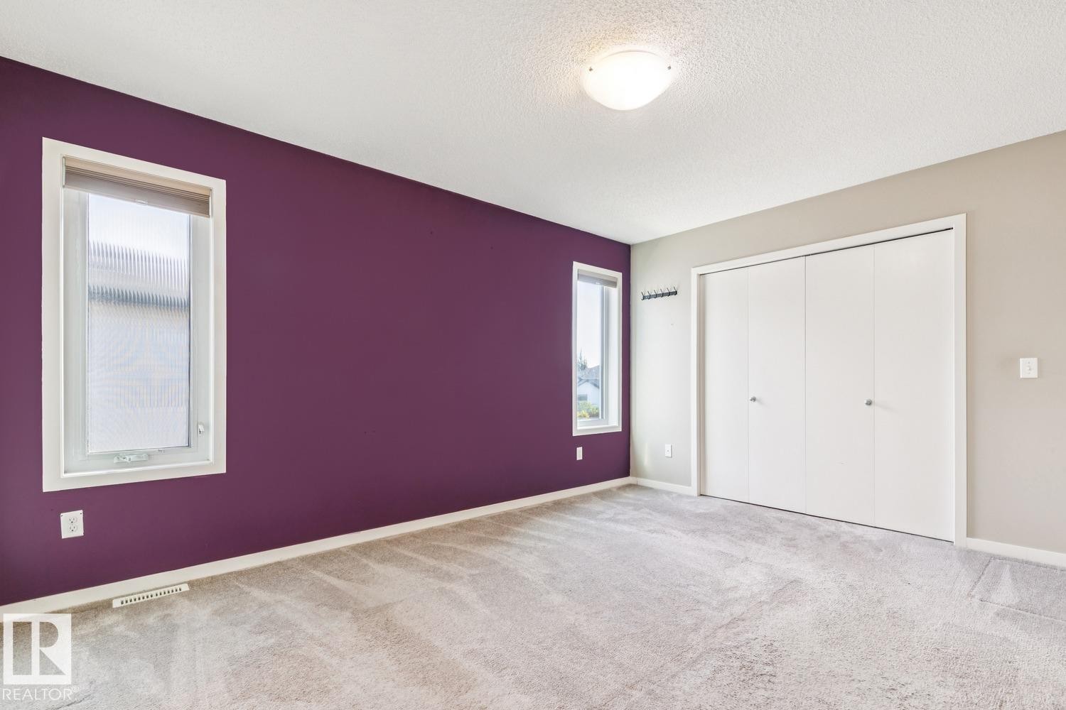 Plush carpeted flooring, a flush-mount ceiling light, white bi-fold closet doors, and two windows - 12007 173 Avenue Nw, Edmonton, AB