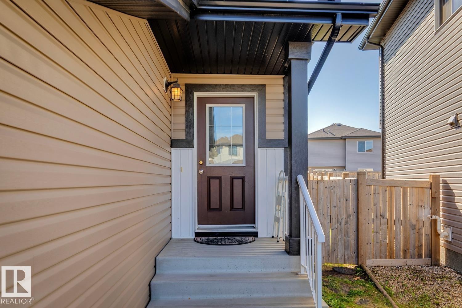 Entryway with concrete steps, white railings, and a dark brown door with an integrated window - 12007 173 Avenue Nw, Edmonton, AB