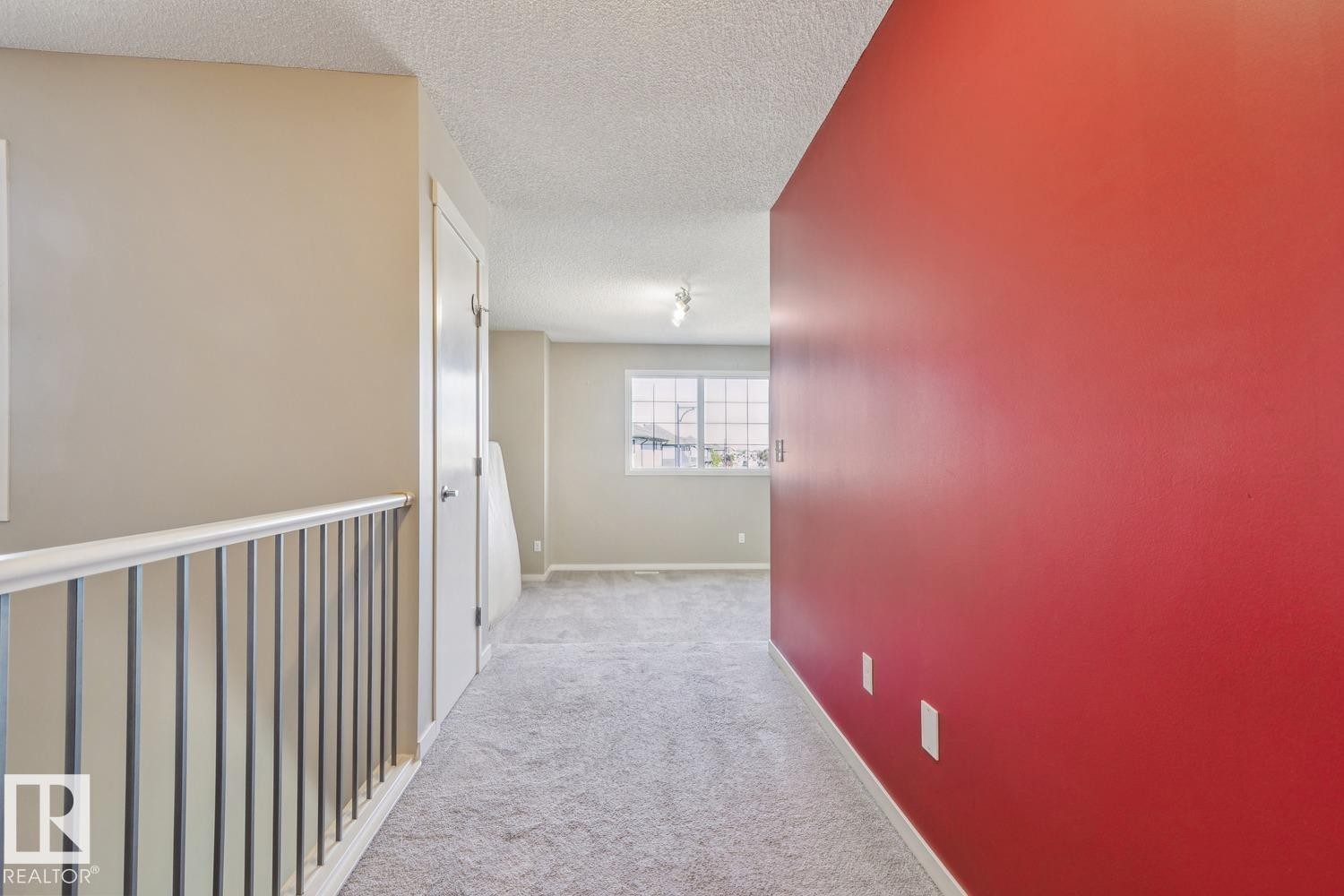 Carpeted hallway featuring a white spindle railing and a window with grid detailing - 12007 173 Avenue Nw, Edmonton, AB
