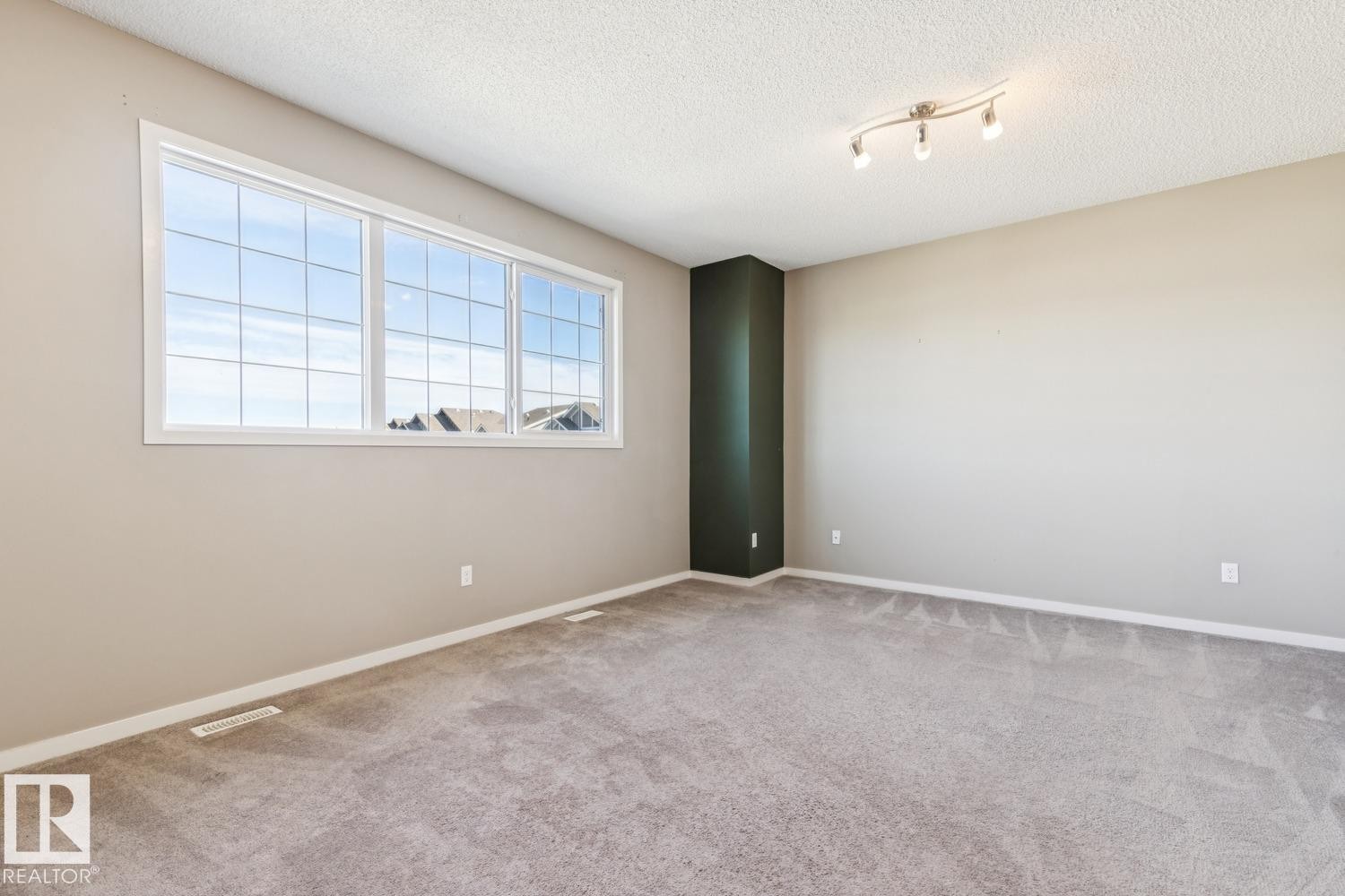Wall-to-wall carpeting, expansive window, light neutral wall paint, accent wall, and track lighting - 12007 173 Avenue Nw, Edmonton, AB