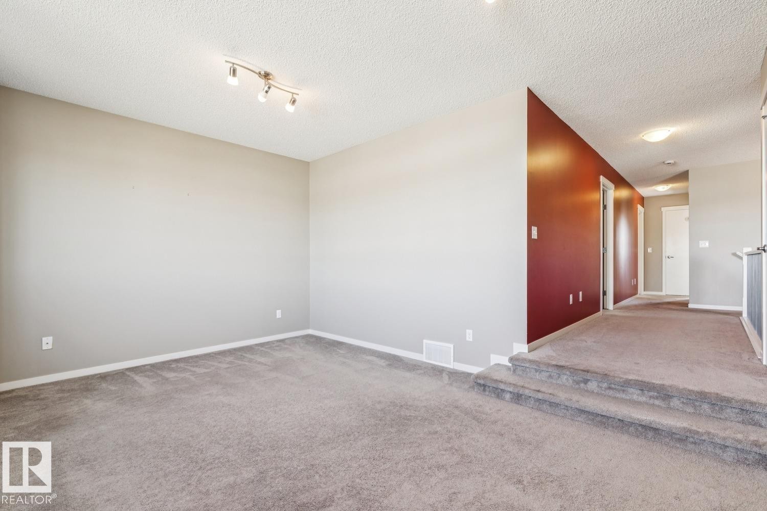 Carpeted room featuring light gray walls and a track light fixture - 12007 173 Avenue Nw, Edmonton, AB