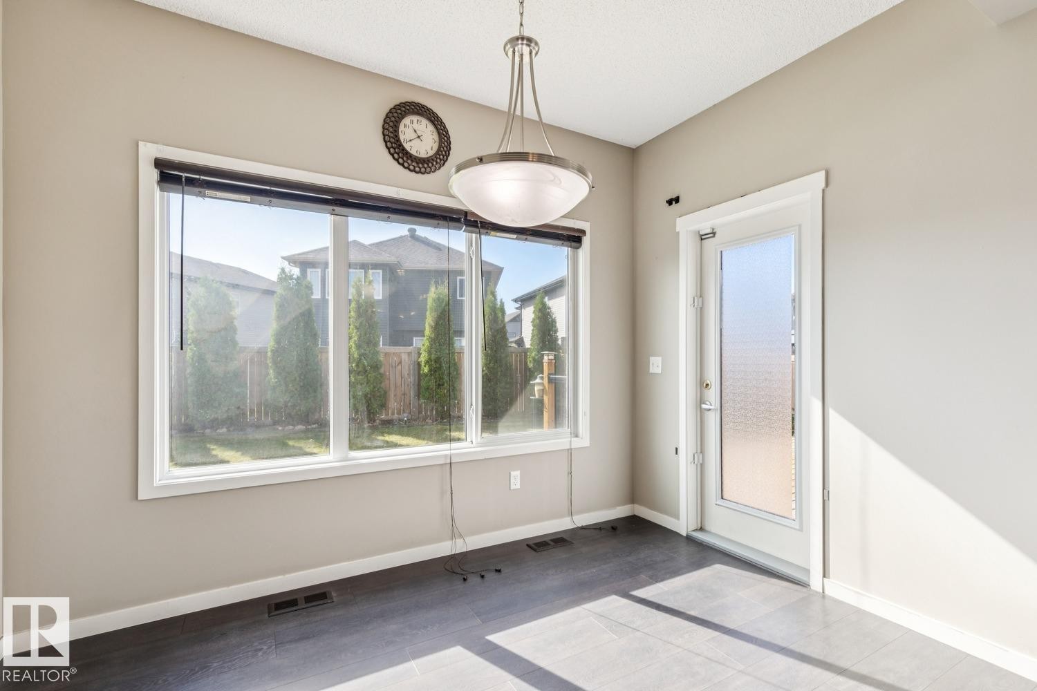 Expansive window featuring a backyard, wood-finish flooring, and a pendant light fixture - 12007 173 Avenue Nw, Edmonton, AB