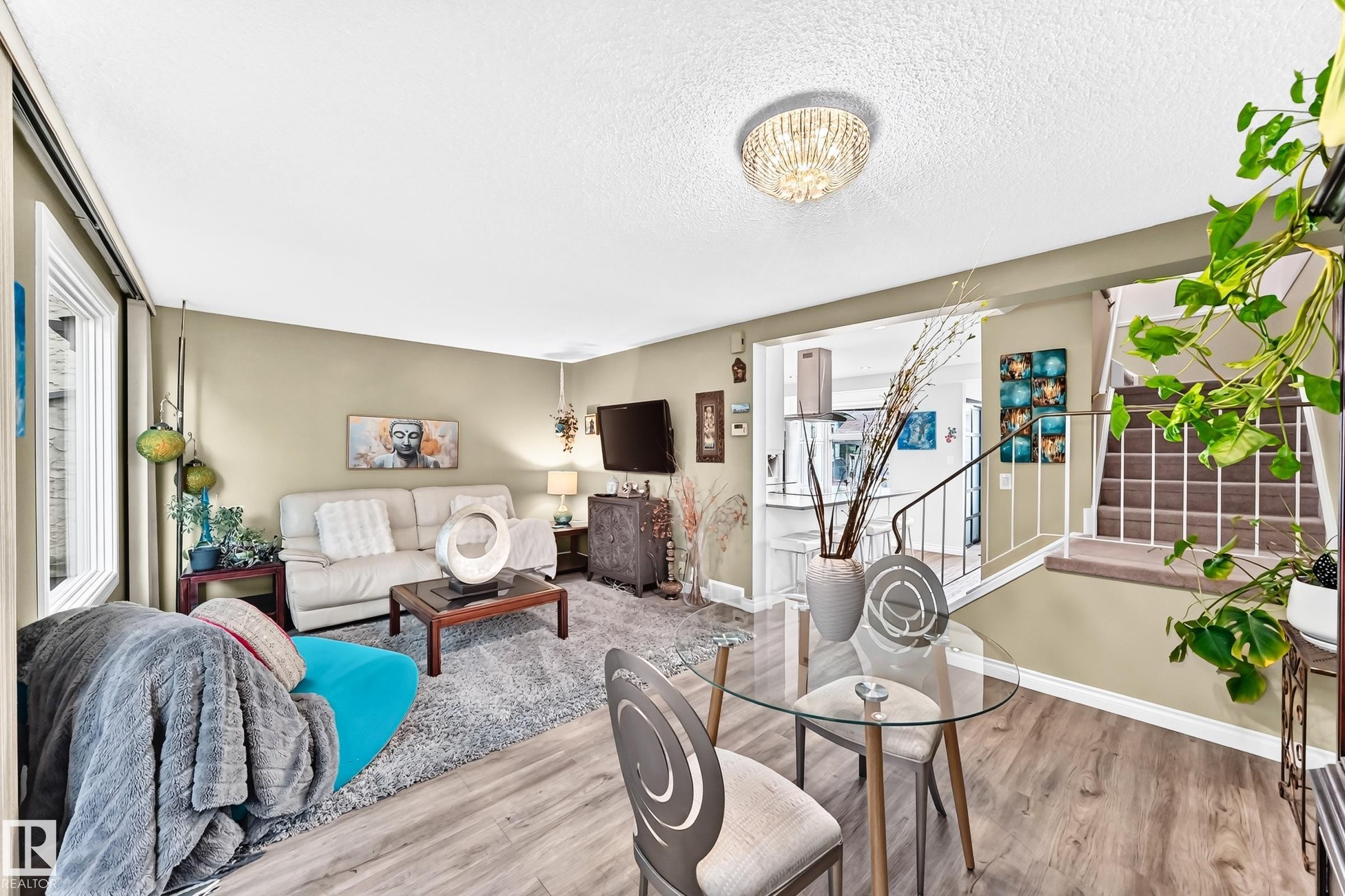 Wood-finish flooring throughout, with a crystal flush-mount ceiling fixture and light neutral wall colors - 5620 93A Avenue Nw, Edmonton, AB